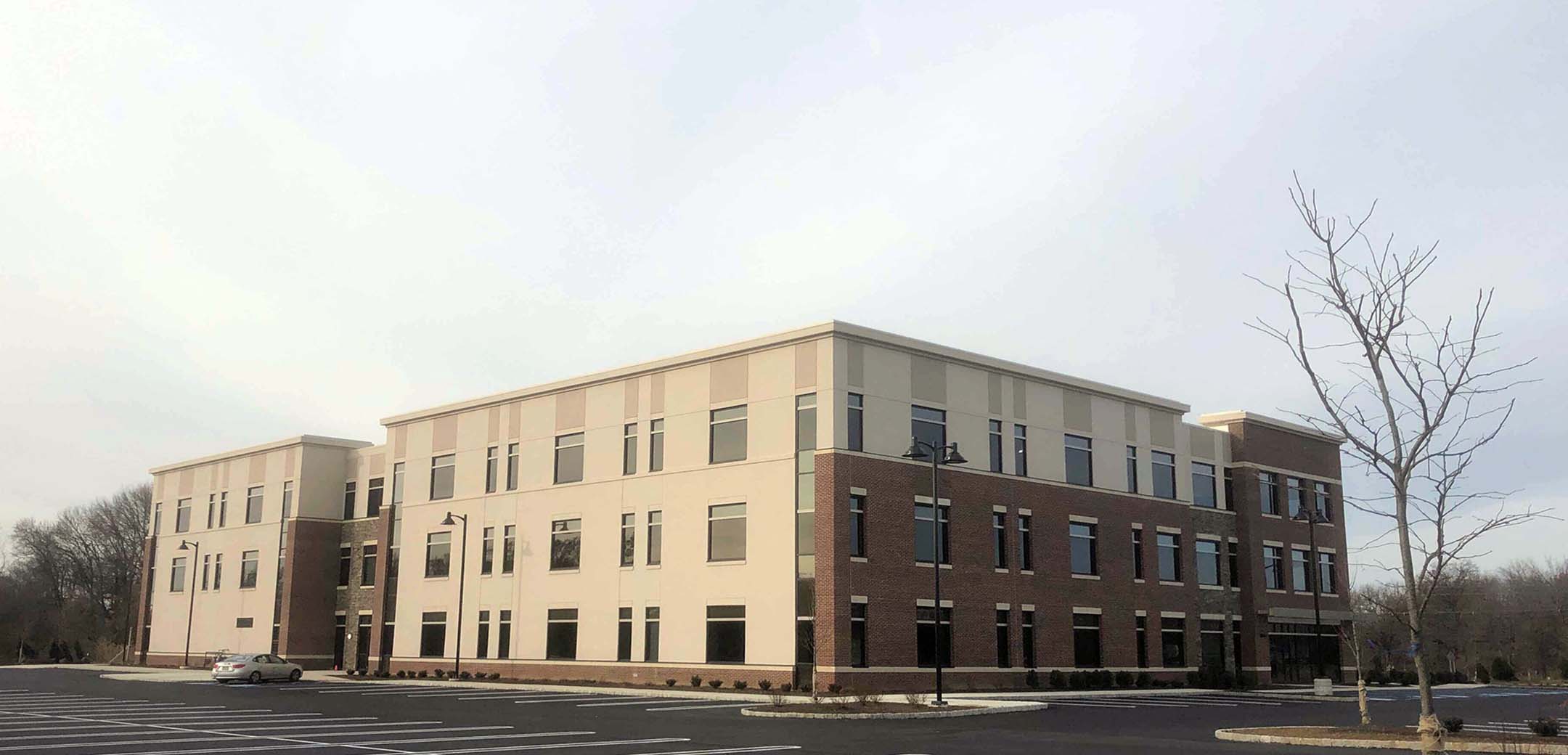 An angle view of Bordentown Medical Office Building with tan stucco exterior and many windows.
