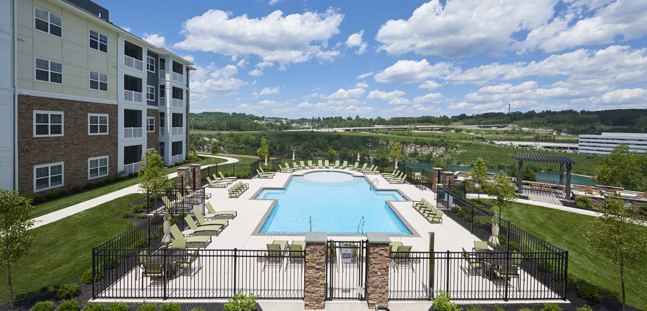 The exterior of the Haven buildings inner courtyard with a large pool and seating around it with a pond and greenery in the background.