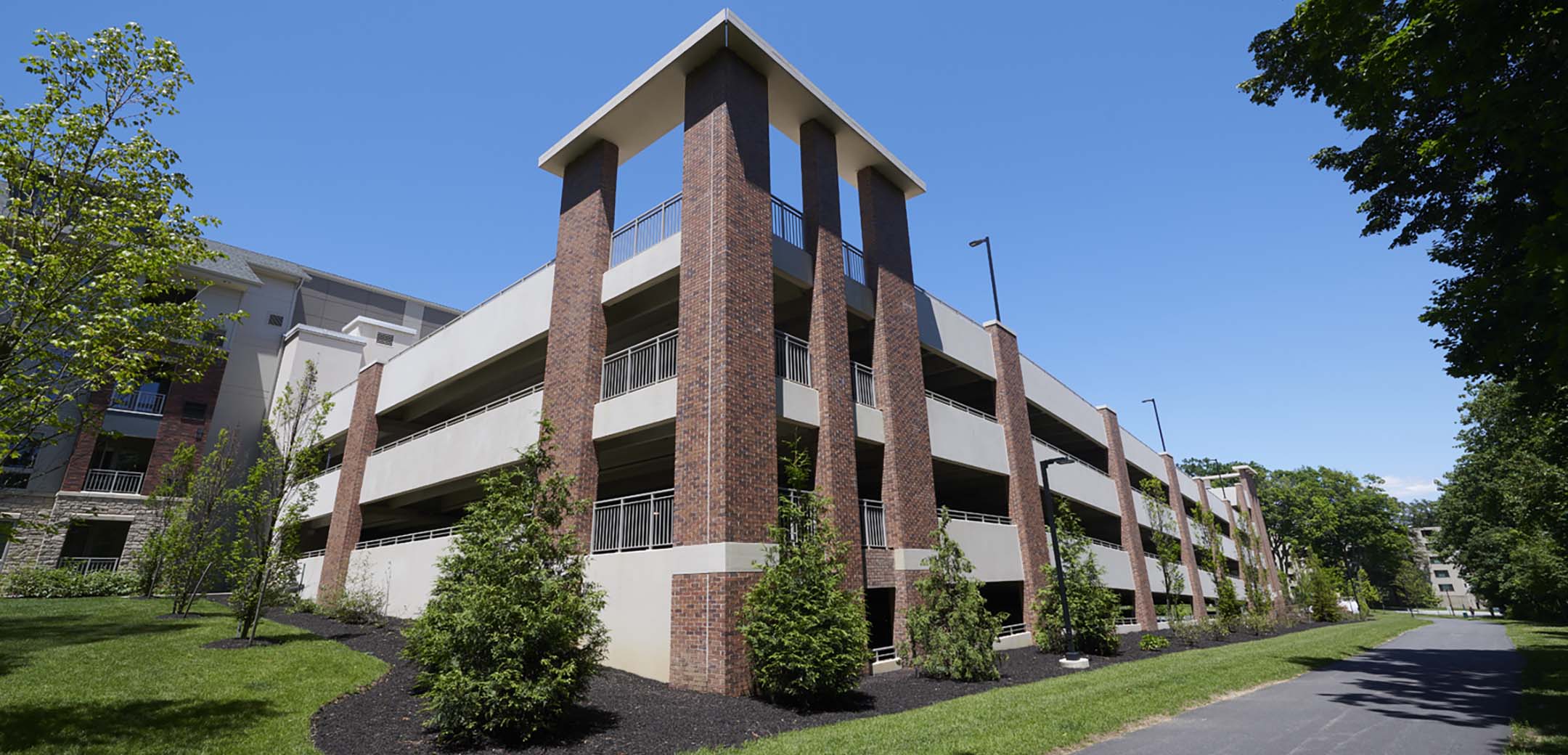An angled view of the Maybrook building parking lot with 3 levels and trees planted along the side road.