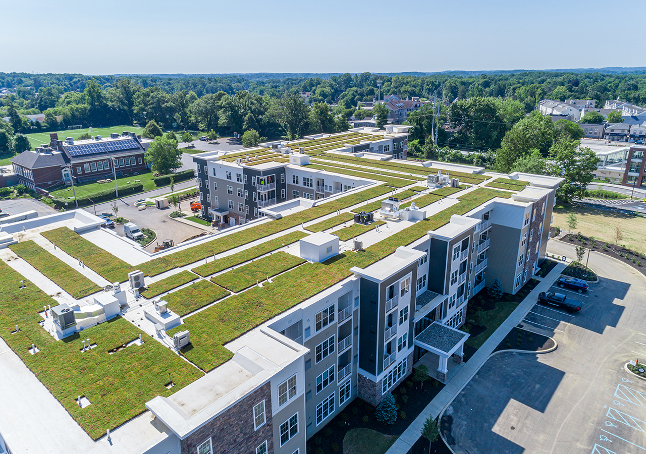 An aerial shot of the Airdrie building, showcasing the large layout, parking amendments, grass roof and the general area.