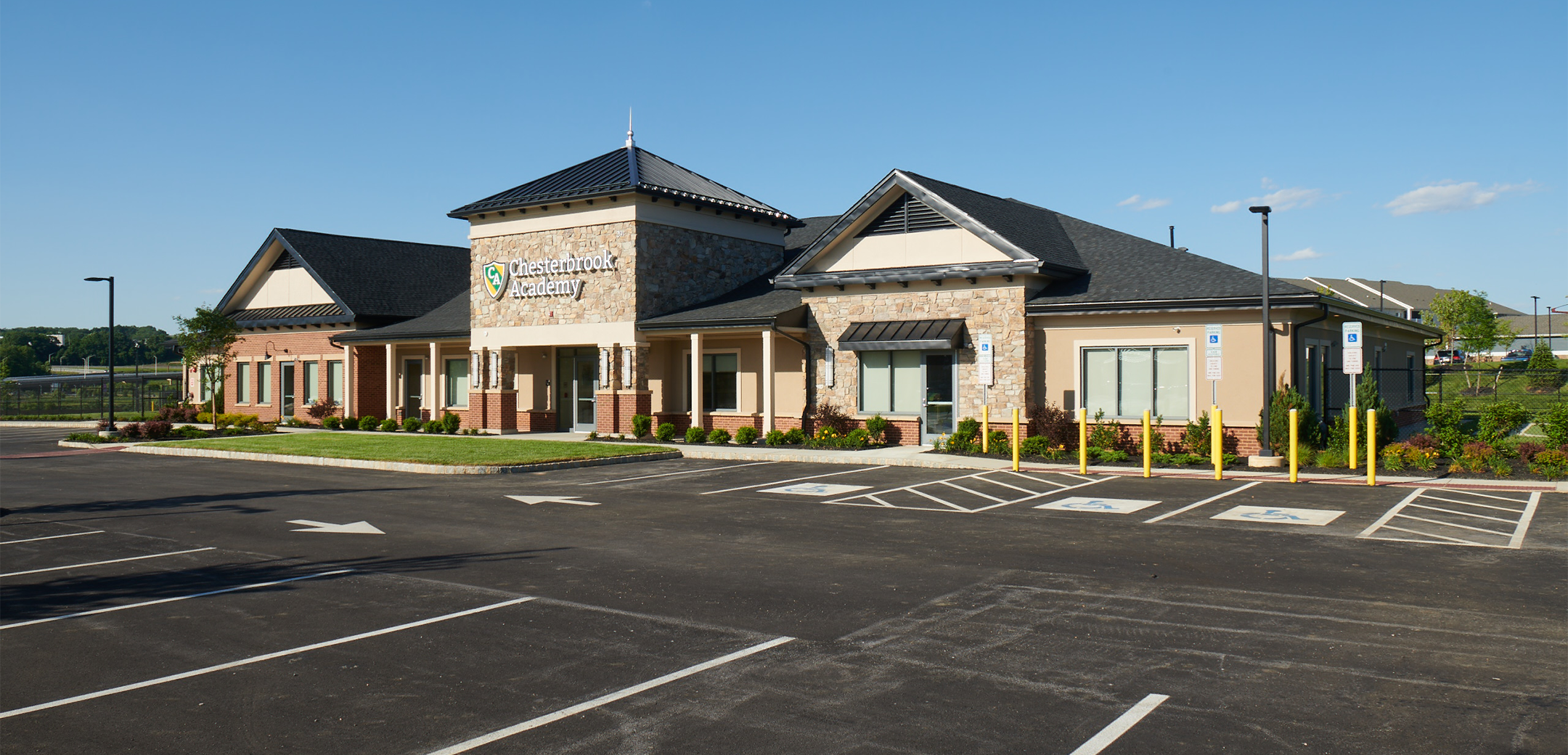 An angled view of the single story Chesterbrook Academy building featuring slanted roofing designs showcasing the front parking lot area.