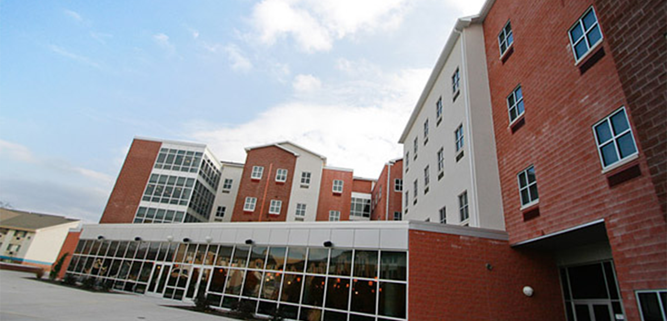 The exterior of the Stage x PA College building showcasing the full length of the building with grass and parking lot in the foreground.