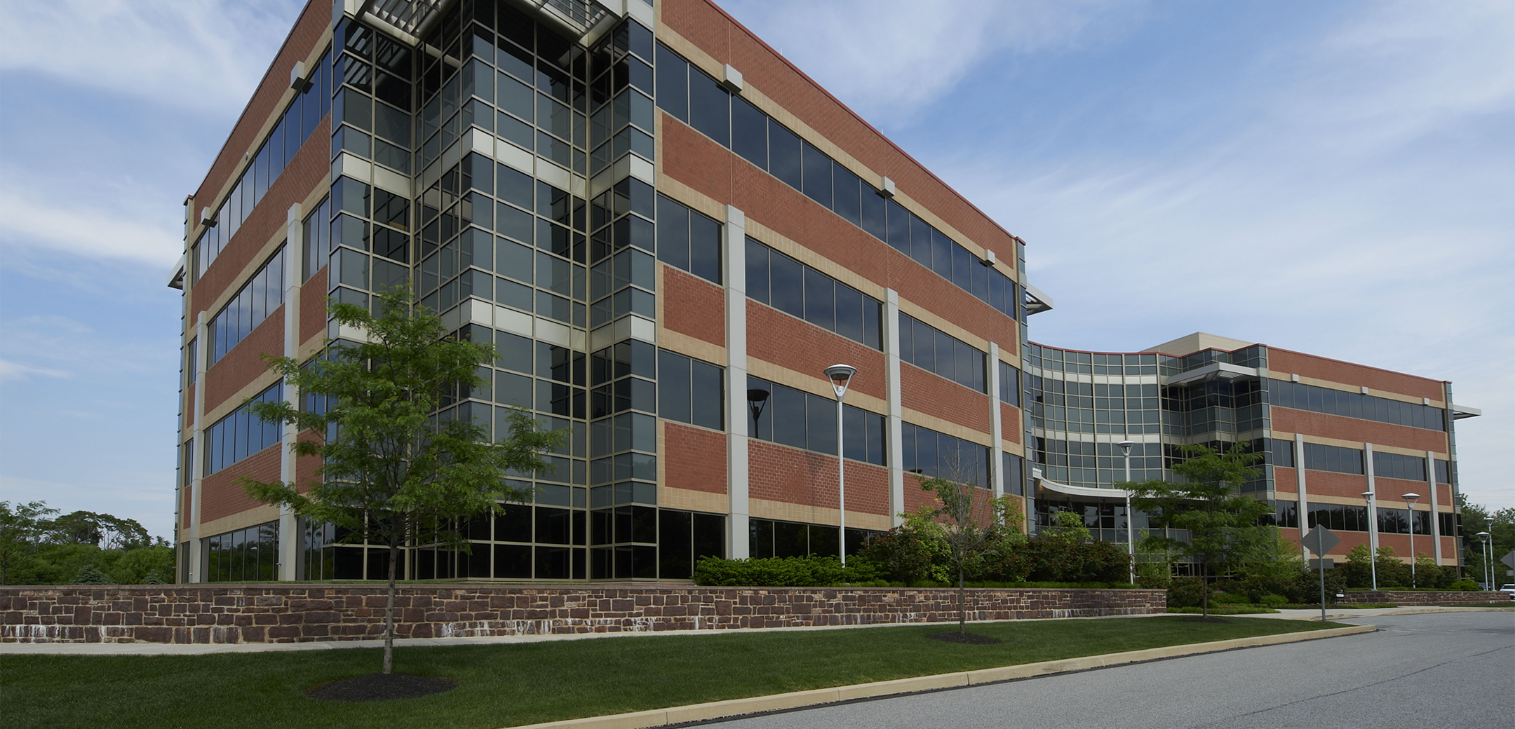 An angled view of the front Floral Vale building featuring all glass panels mixed with orange accent panels, showcasing the front entrance.