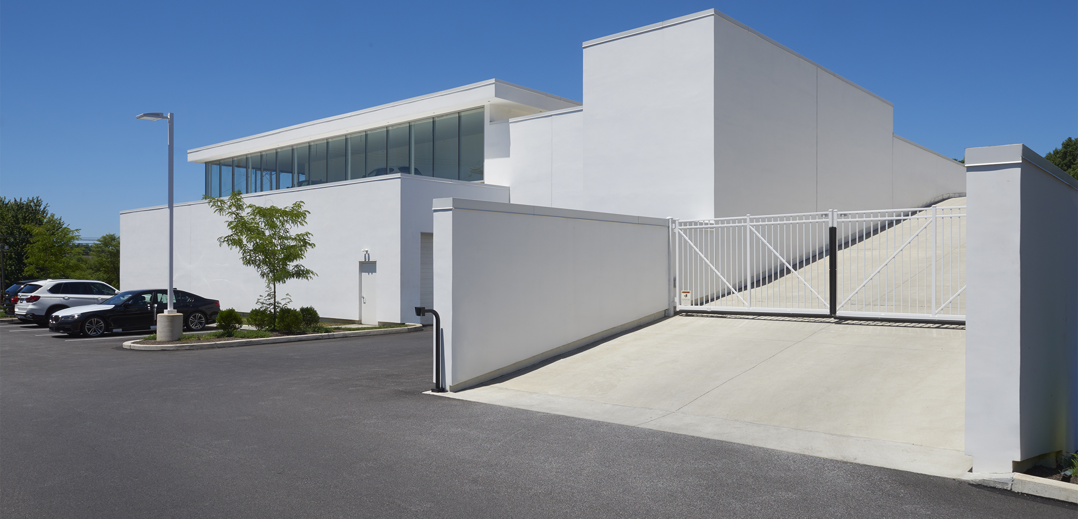 The exterior view of the Ottos BMW back view showcasing the white building back exit and upwards going ramp in the foreground.