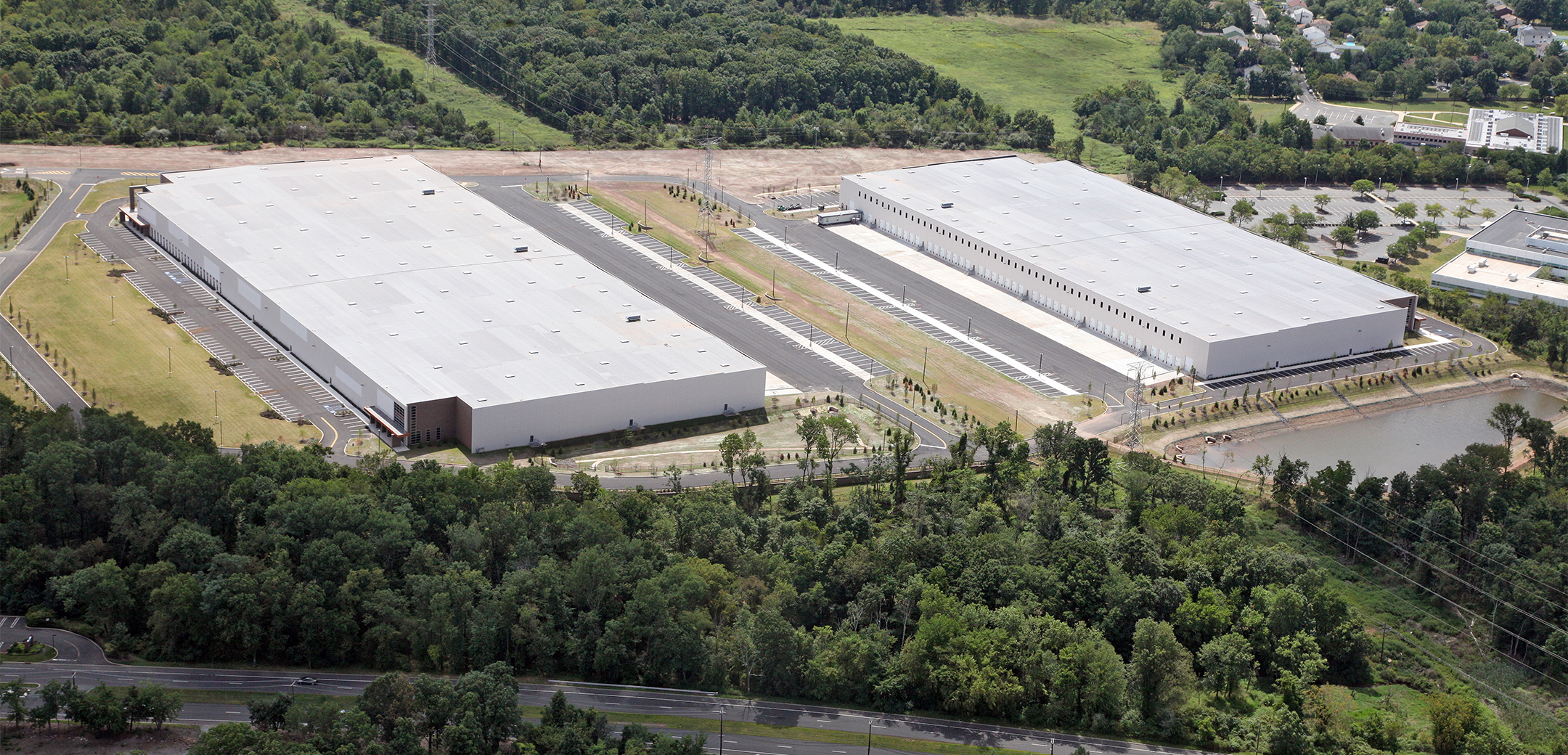 An aerial view of the South Washington Park buildings showcasing the two warehouses, parking lots, side pond, main road, and overall layout.